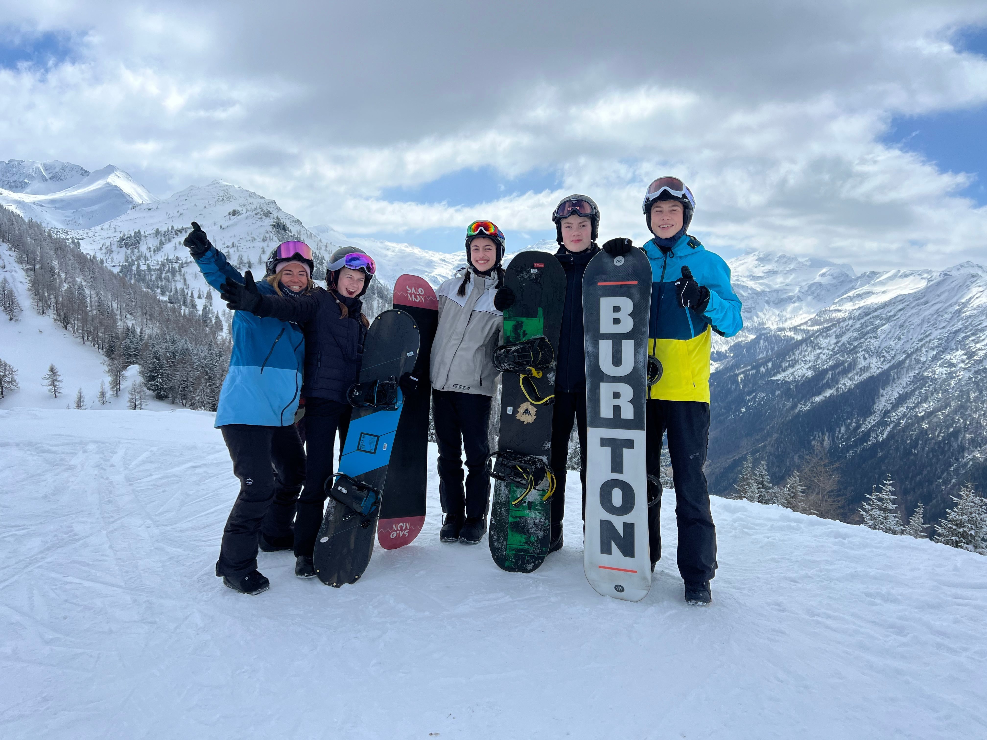 Personengruppe posiert im Schnee für Foto mit Snowboards in den Händen